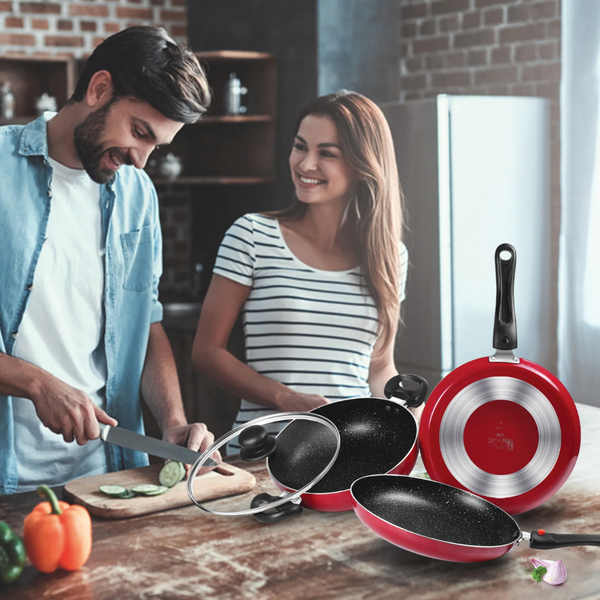 Man and woman in a kitchen with red and black frying pans on a counter.