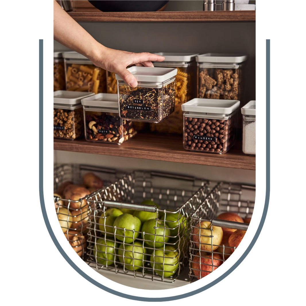 Person reaching for a container of snacks on a kitchen shelf with various food items.