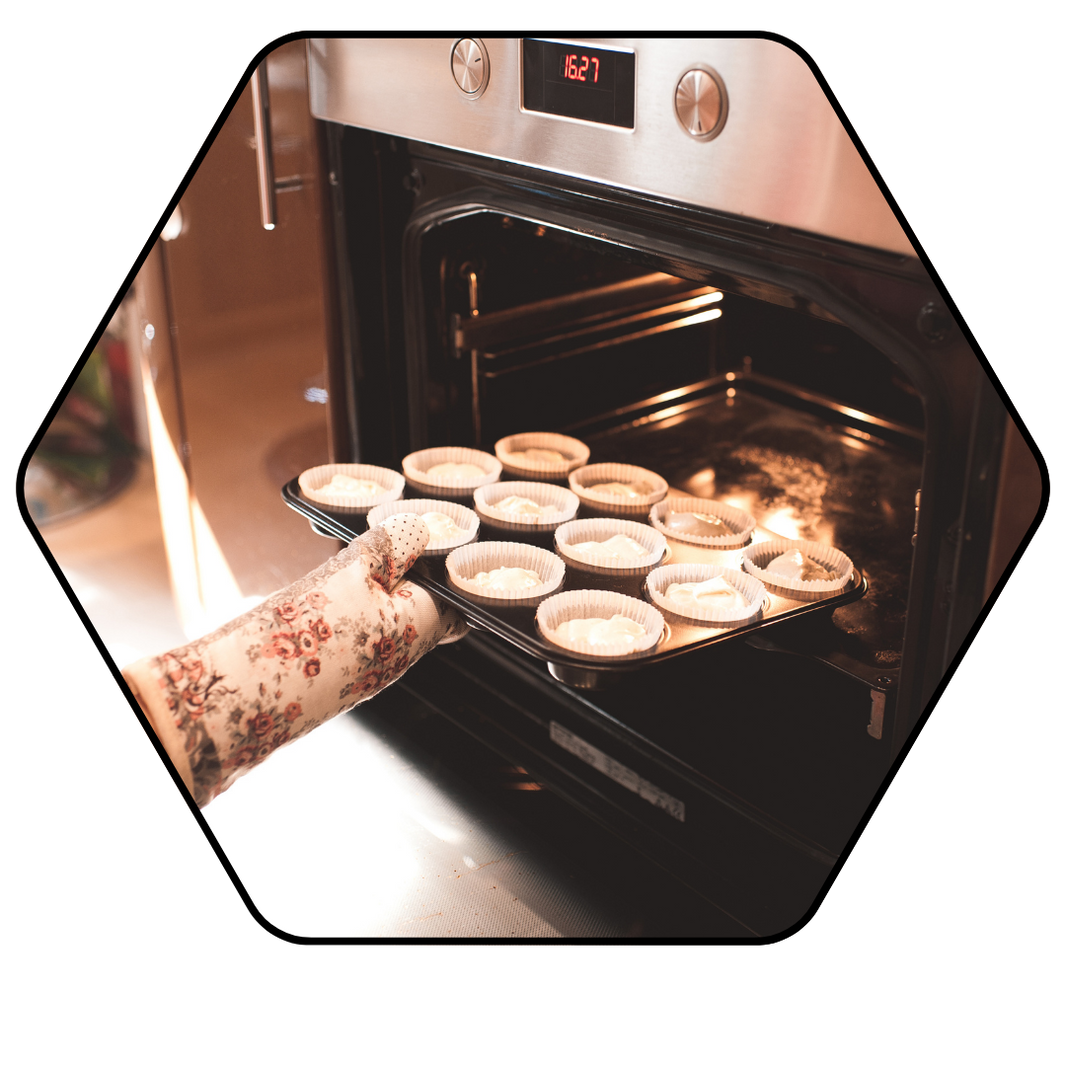 Person taking a tray of cupcakes out of an oven.