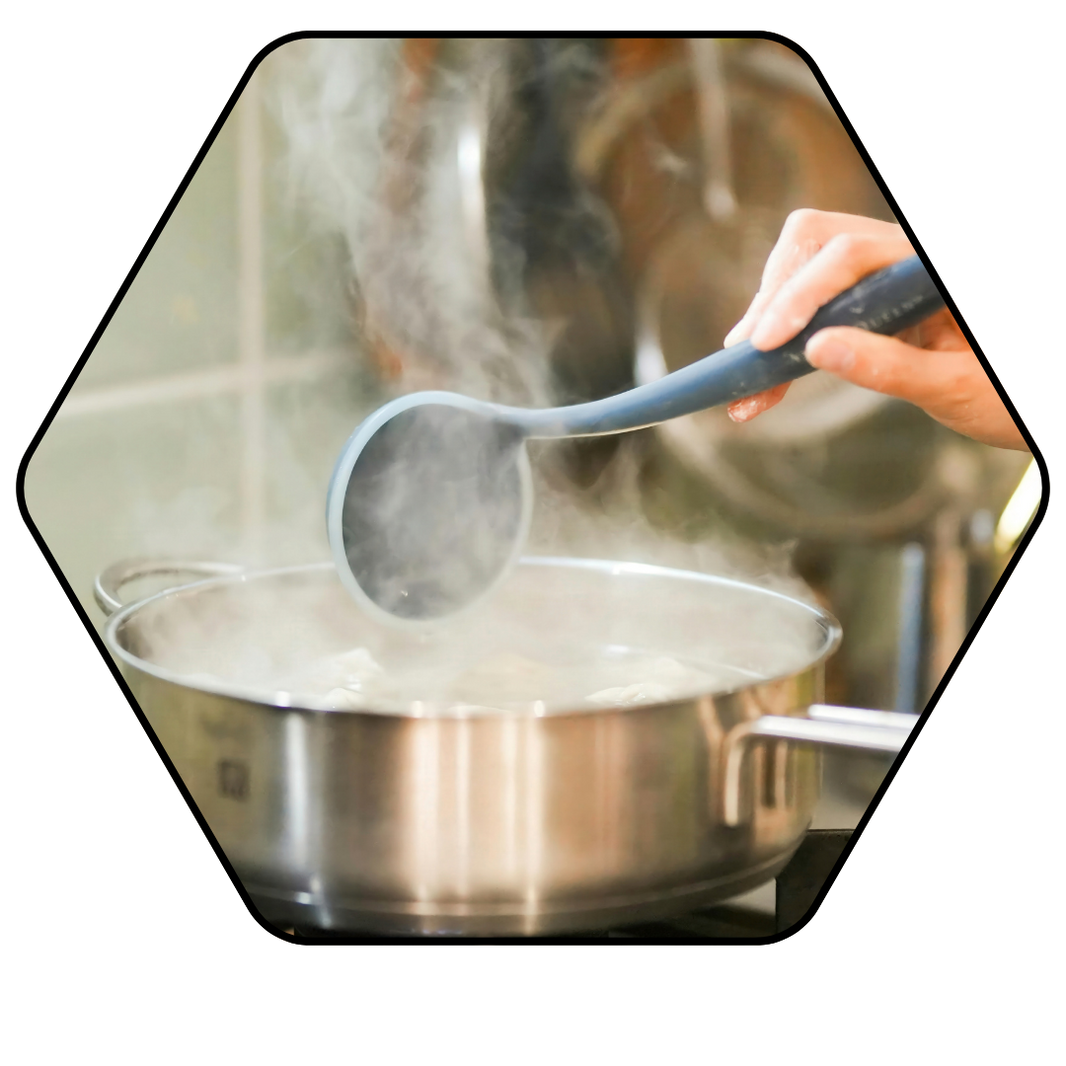 Person stirring a pot with steam rising, indicating cooking activity.
