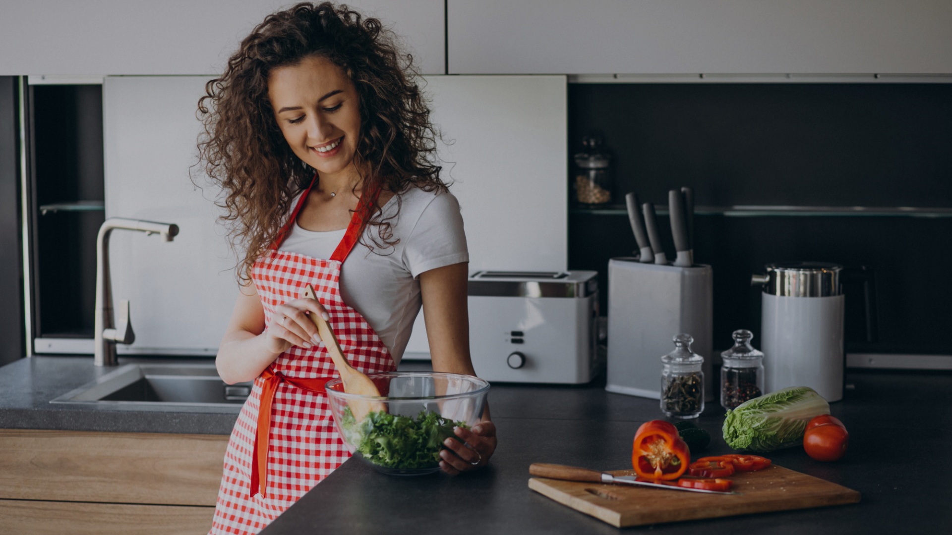 Woman in a kitchen preparing food with various ingredients on the counter.